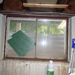 An old, rusted basement window with a steel frame in Eau Claire.