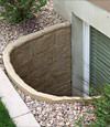 A durable plastic egress window well installed in a rock garden in Janesville.